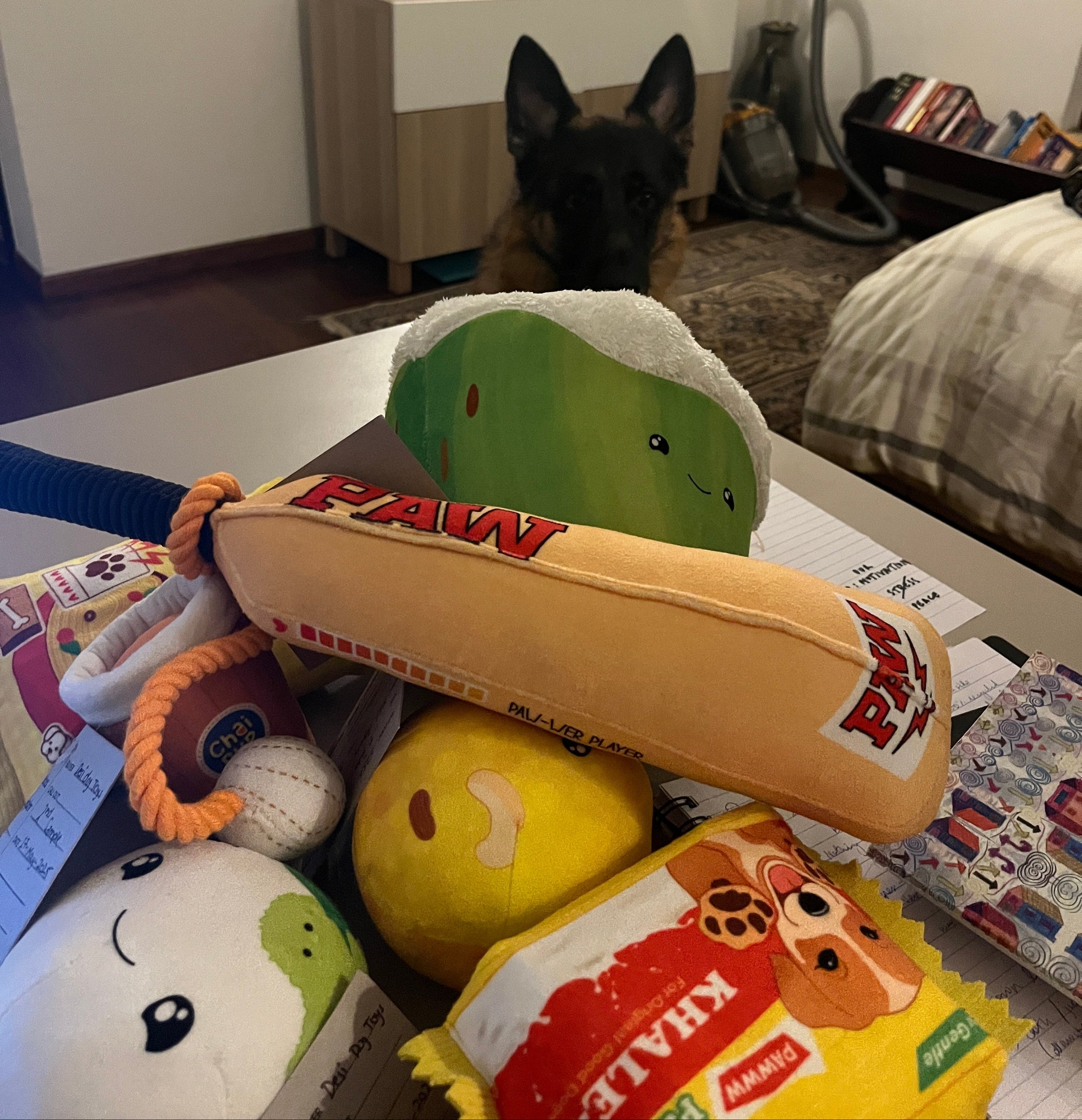 Collection of plush toys on a surface with a dog peeking from behind.