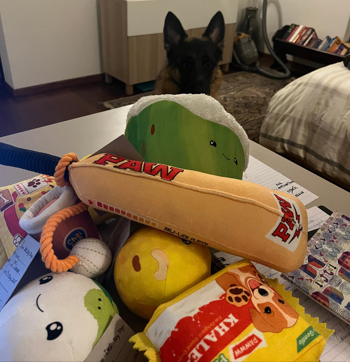 Collection of plush toys on a surface with a dog peeking from behind.